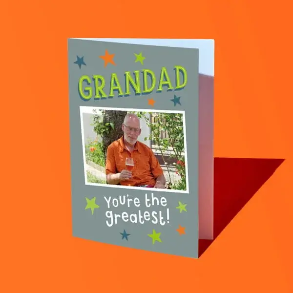 A personalised greeting card reading Grandad You’re the greatest, featuring a framed photo and star decorations, displayed against a bright orange background.